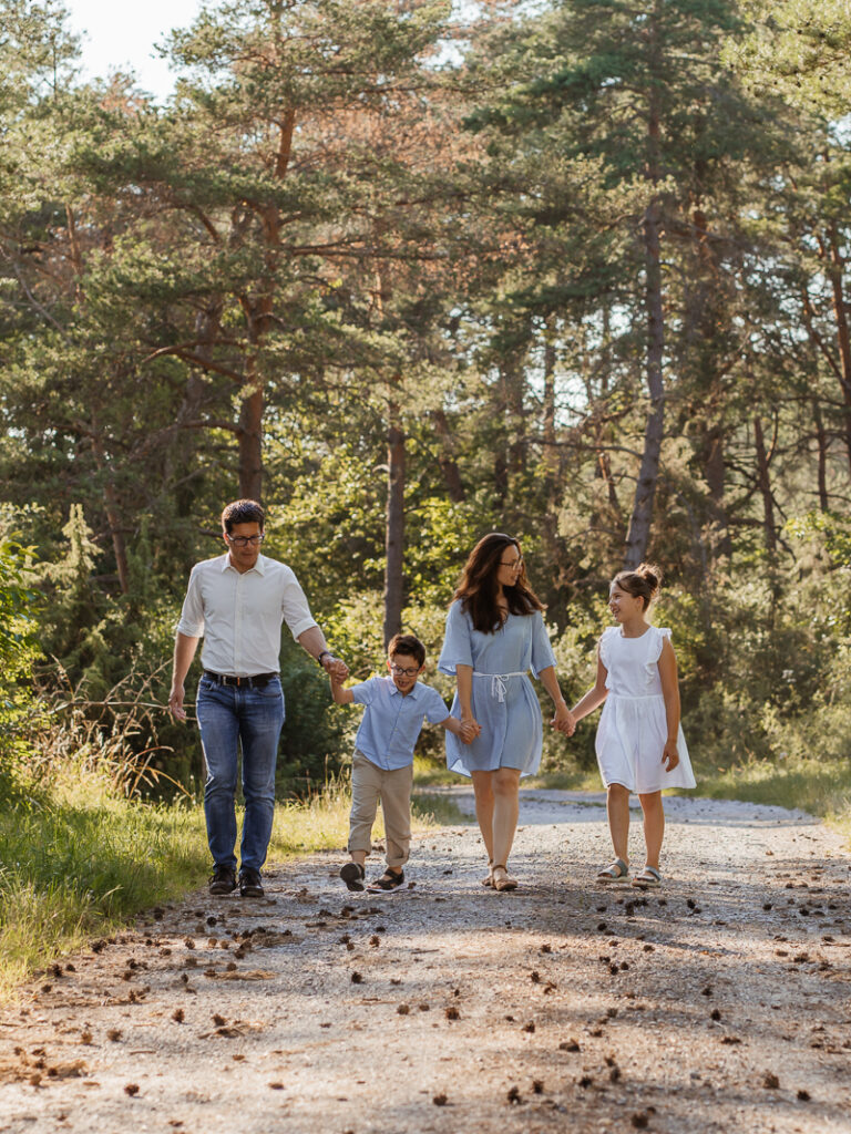 Familie lacht und schaut sich gegenseitig an während sie einen Spaziergang im Wald machen bei einem Outdoorshooting in Main Spessart