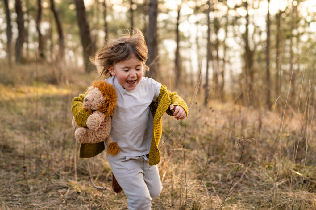 Ein Kind rennt lachen auf die Kamera zu bei einem Familienshooting im Sonnenuntergang in Main Spessart