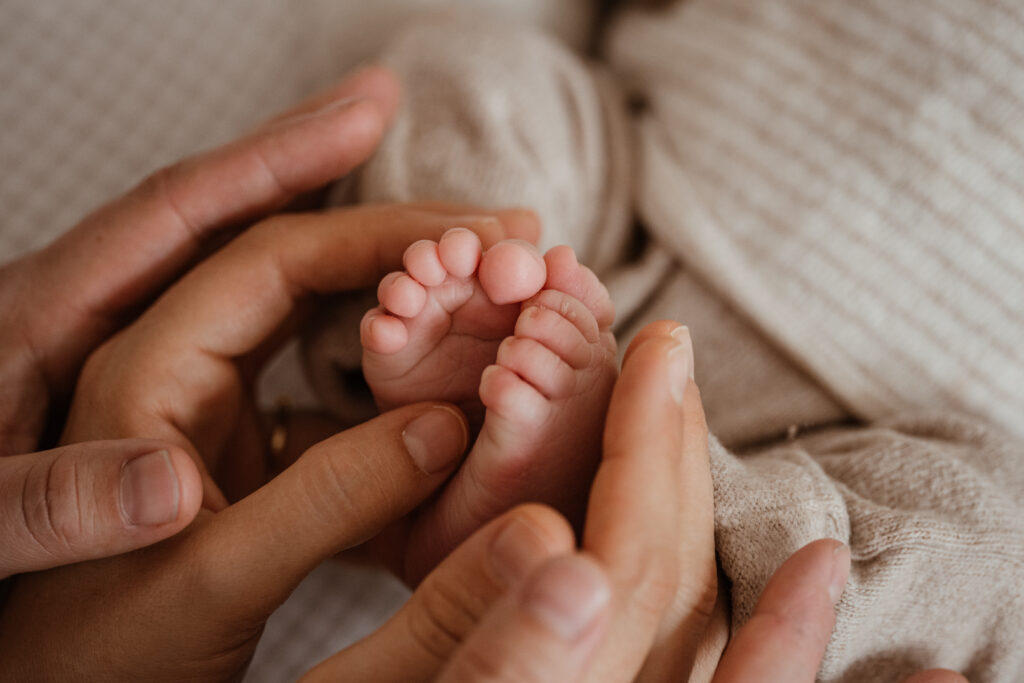 Eltern halten Füße von ihrem neugeborenem Baby im Tageslichtatelier in Kreuzwertheim