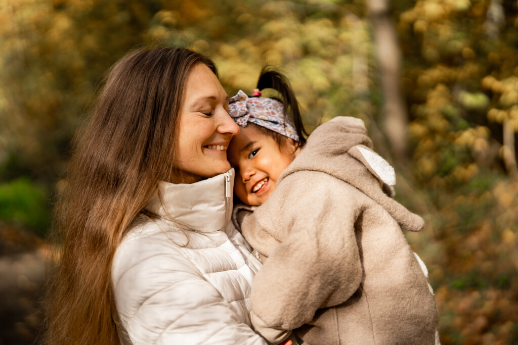 Eine Mutter hält ihr Kind auf dem Arm, welches in die Kamera strahlt, bei einem Mommy and Me Shooting in Main Spessart