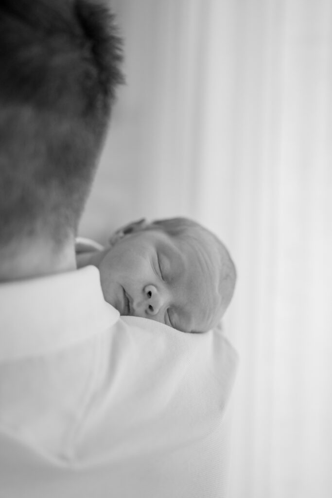 Neugeborenes Baby schläft auf der Schulter vom Vater bei einem Babyshooting im Studio in Kreuzwertheim