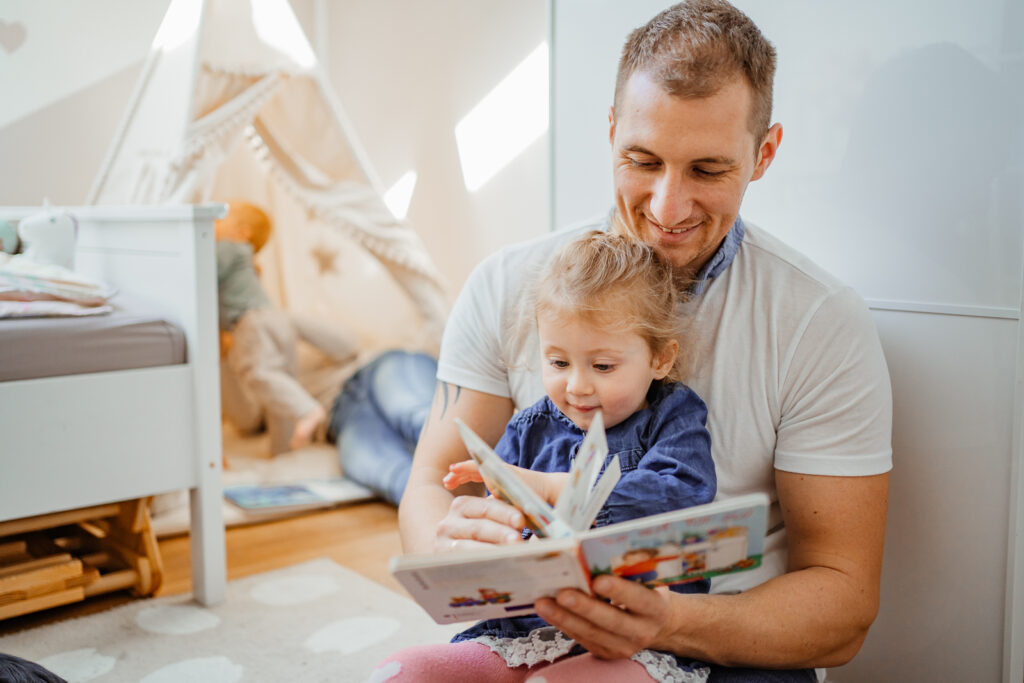 Papa liest mit Kleinkind ein Buch bei einer natürlichen Homestory in Marktheidenfeld