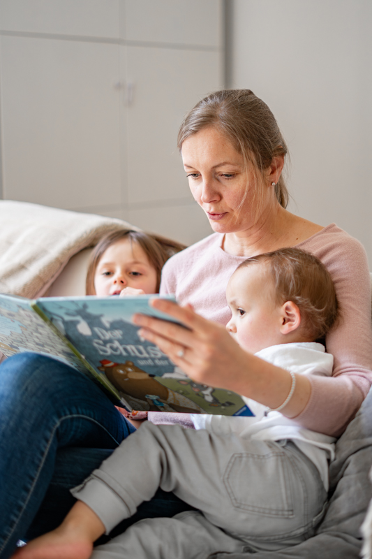Mama liest mit ihren Kindern auf dem Sofa