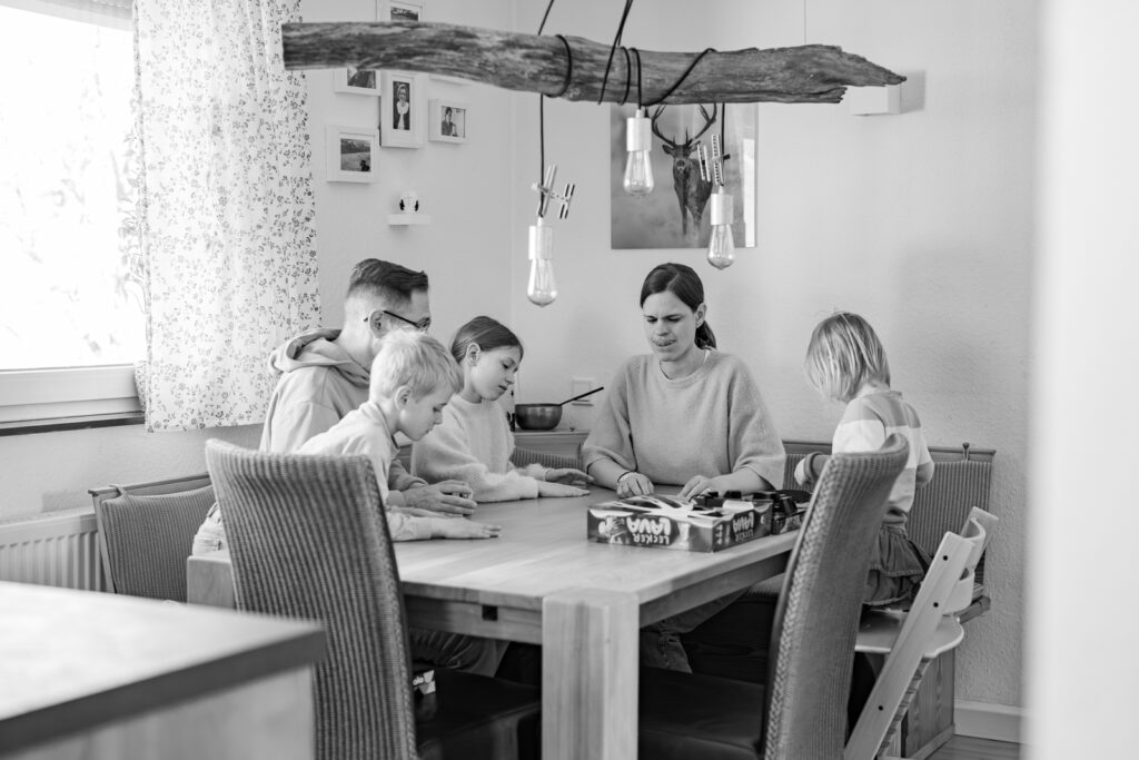 Familie spielt zusammen ein Kartenspiel bei einer Homestory in Würzburg