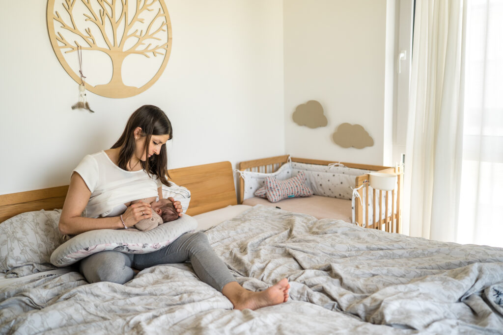 Mutter stillt ihr Neugeborenes auf dem Bett
