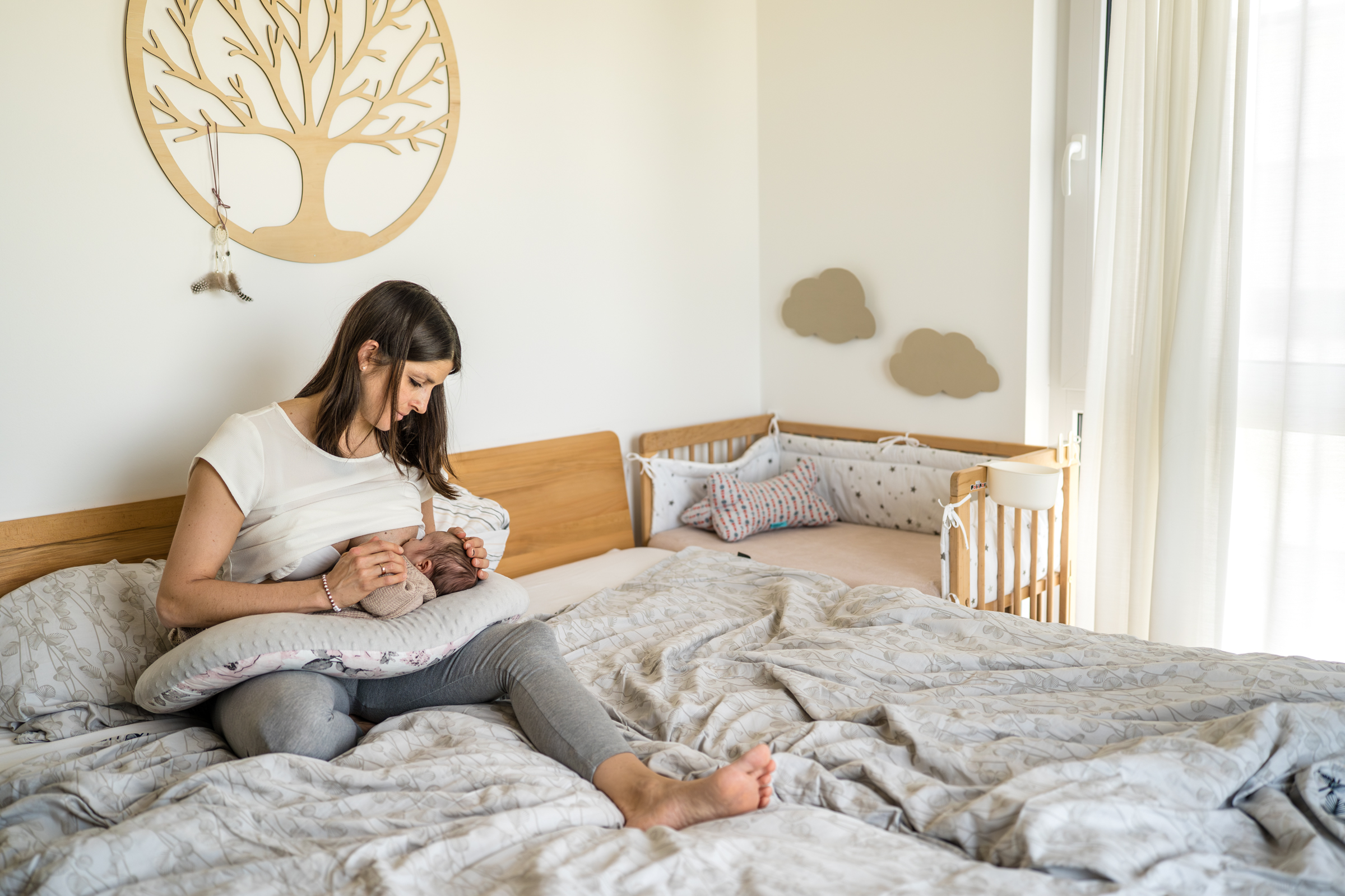 Mutter stillt ihr Neugeborenes auf dem Bett