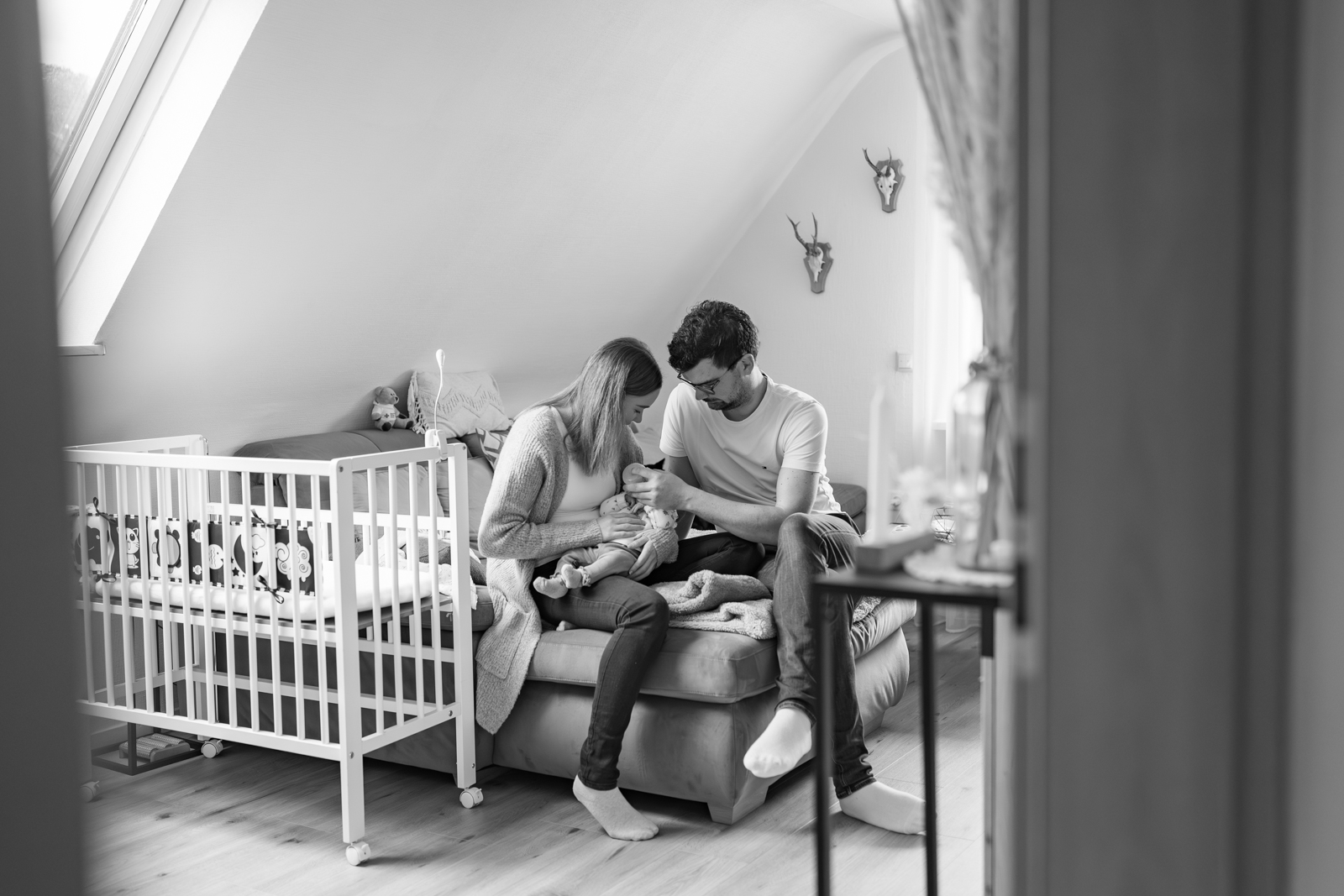 Eltern füttern ihr Baby bei einer Homestory in Main Spessart. Blick von außen in das Wohnzimmer.