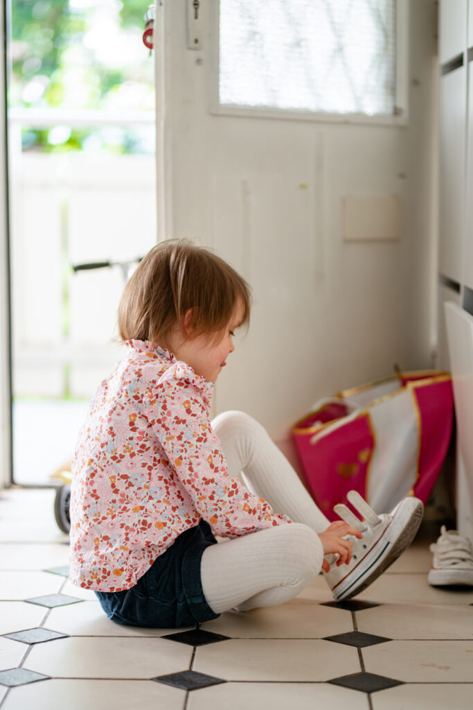 Kind zieht selbstständig ihren Schuh bei einer Homestory im dokumentarischen Stil in Main Spessart an