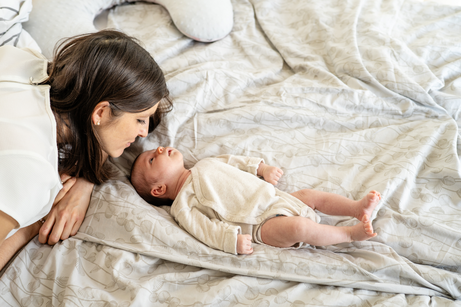 Frischgebackene Mama kuschelt mit ihrem Baby im Wochenbett