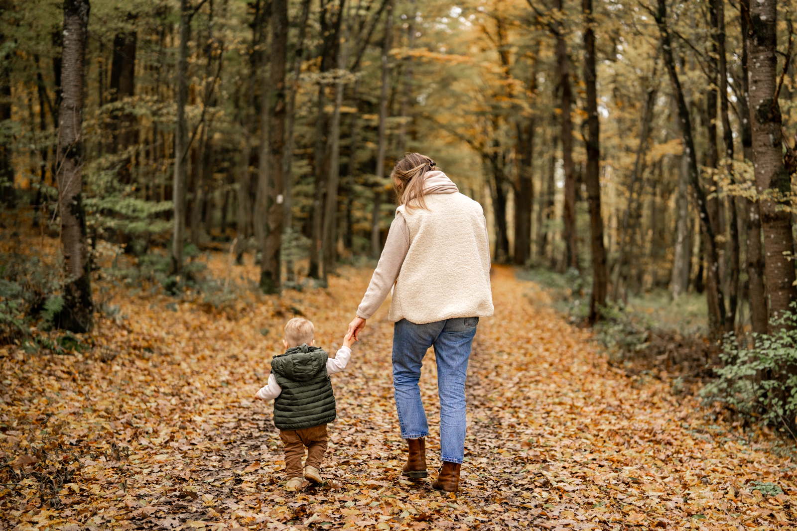 Mutter läuft mit Kind durch den herbstlichen Wald